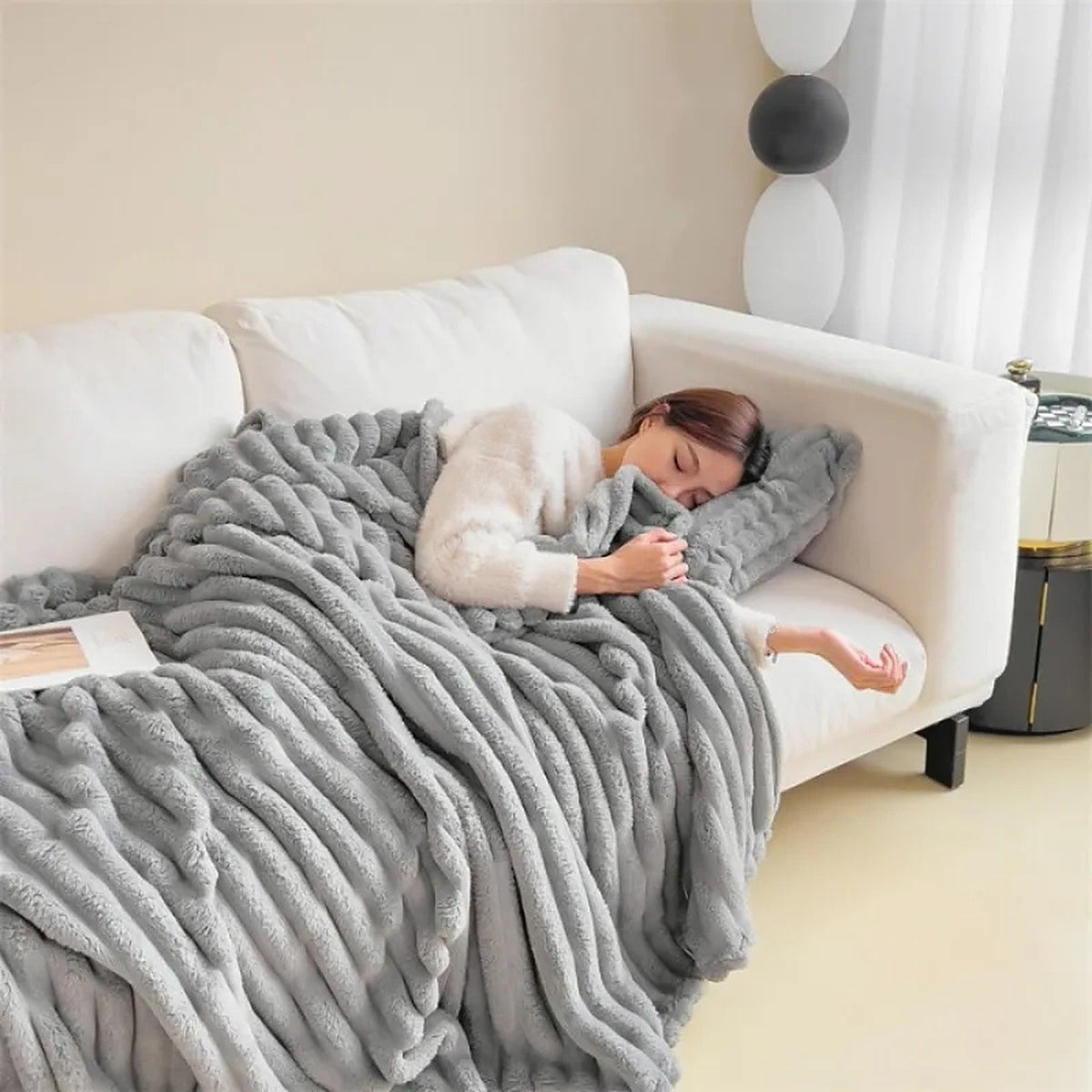 Plaid Oniria gris perle sur un canapé